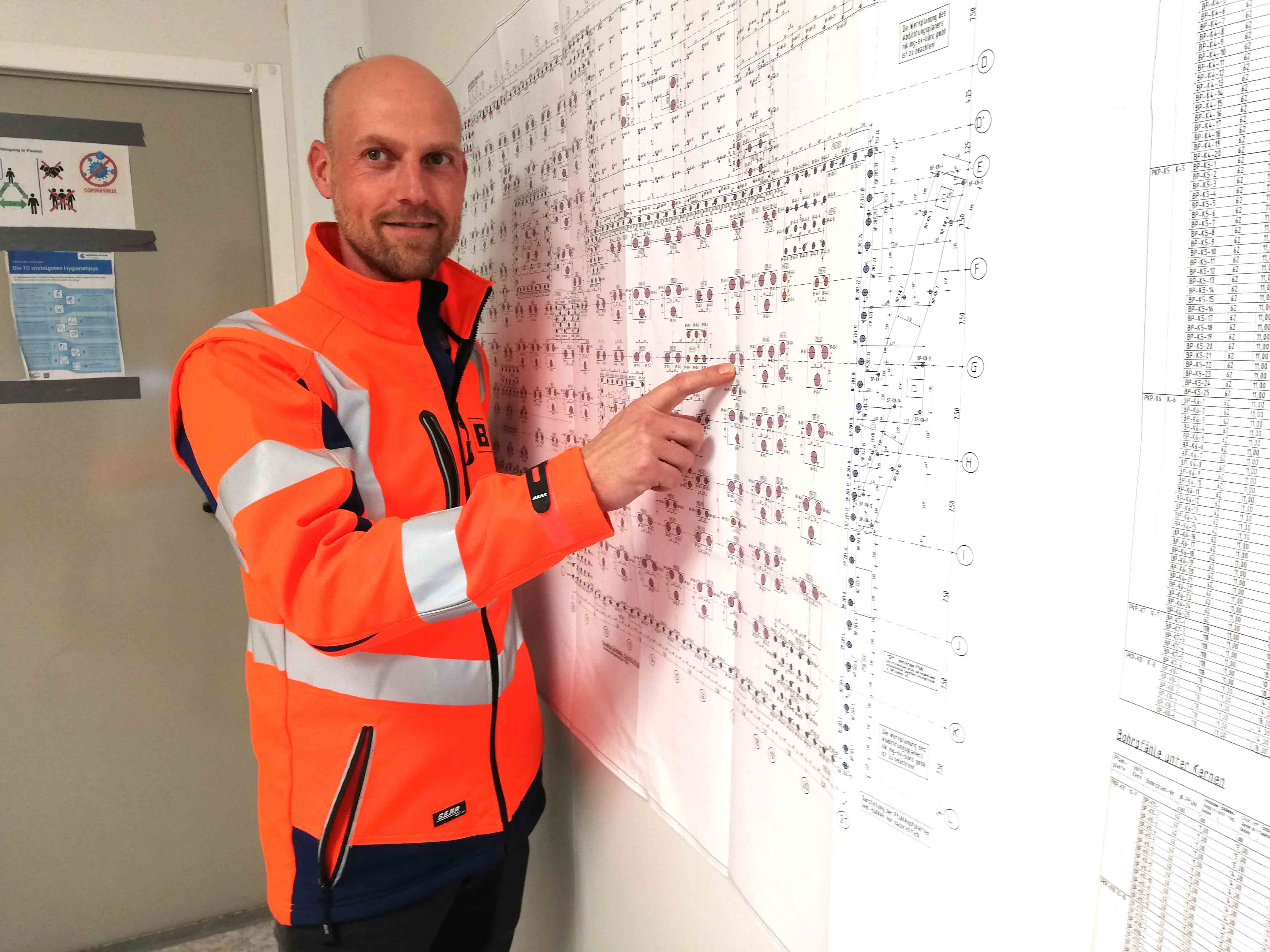 Der 41 Jahre alte Bauingenieur Alexander Böttiger ist Bauleiter der Firma Berger in Wilhelmshaven; er zeigt auf die Pläne, auf denen die 911 Bohrlöcher für die Stahlbetonpfähle verzeichnet sind, die im Zuge der Tiefgründung vorgesehen sind. Foto: MichalskiMedia